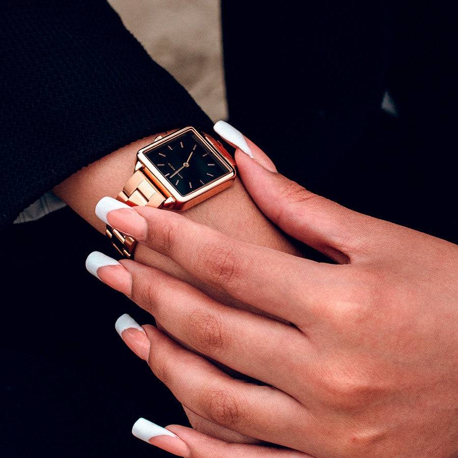 a woman's hands with white nails and a gold watch
