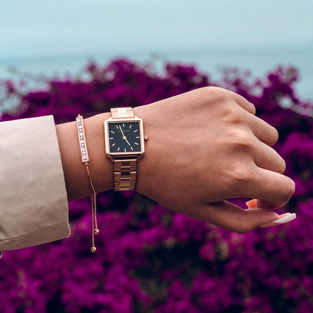 a person wearing a watch and a chain bracelet